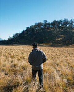 A solitary hiker explores a serene grassy landscape in East Java, Indonesia.